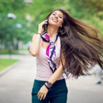 Young, happy girl is walking in the city and talking using her mobile phone